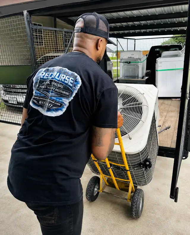 Recourse crew member moving an old AC unit on a dolly