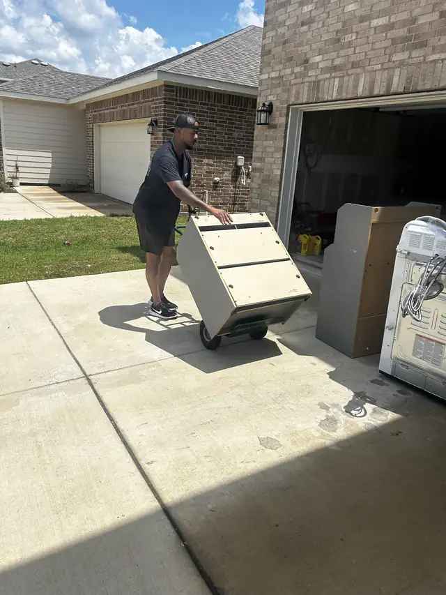 Recourse crew member wheeling an appliance down a driveway