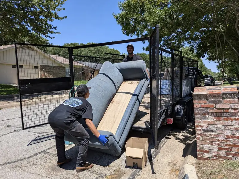 Recourse crew loading a couch into the junk removal trailer