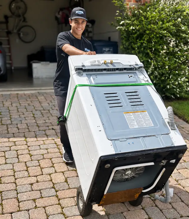 Recourse crew member wheeling a dryer down a driveway on a dolly