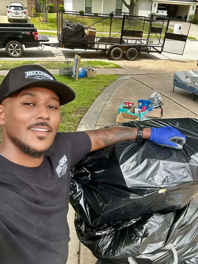 Recourse owner loading bagged junk with the trailer behind him