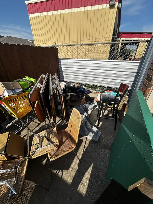 Patio area crowded with old chairs, tables and junk before removal