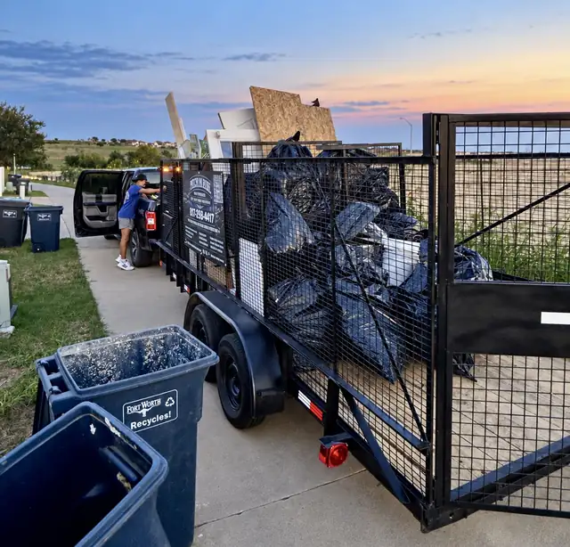 Recourse trailer filled with bagged trash next to residential trash carts
