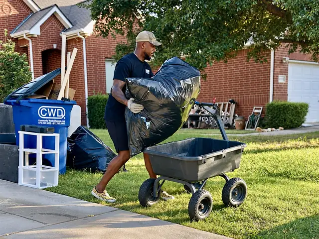 Recourse crew member loading a heavy bag of debris into a yard cart